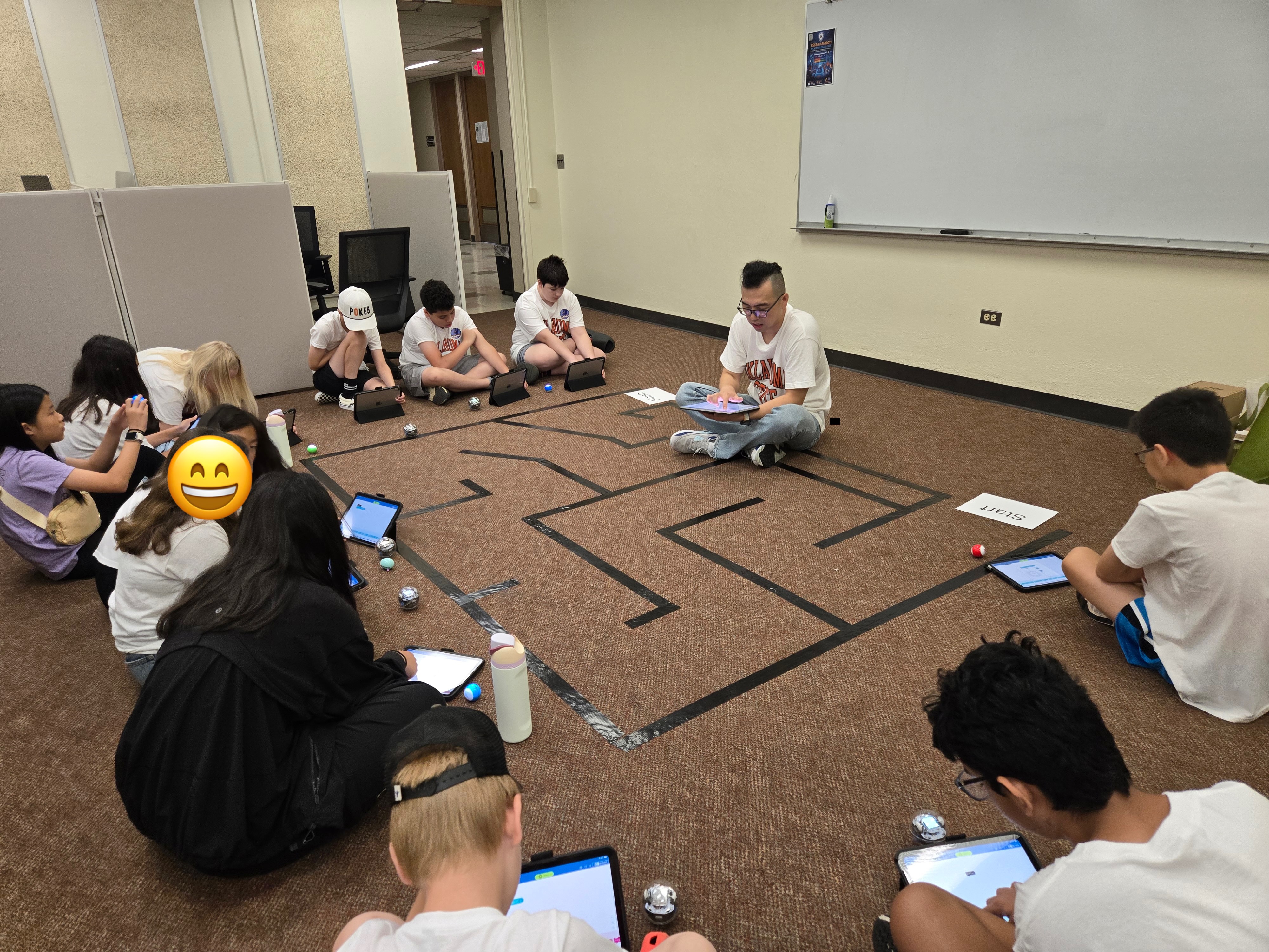 Students are on the floor working with small programmable robots.