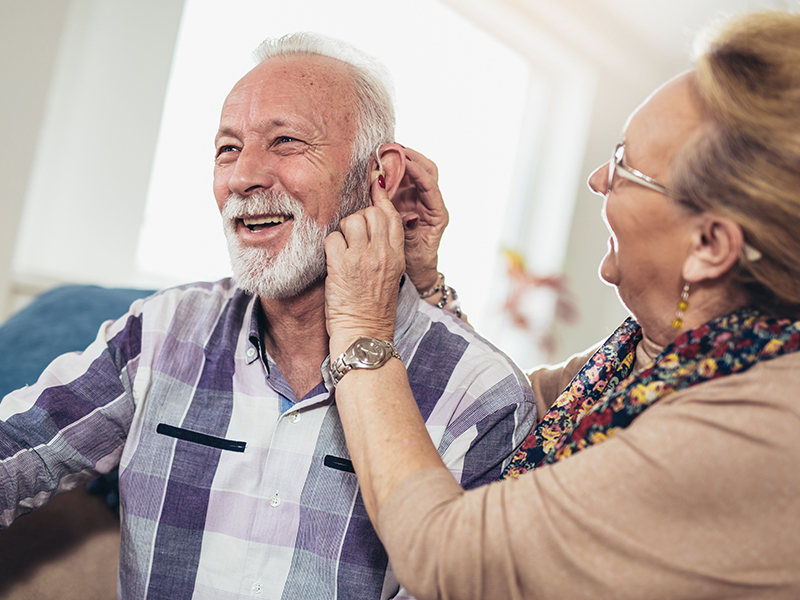 Woman helping man with hearing aids