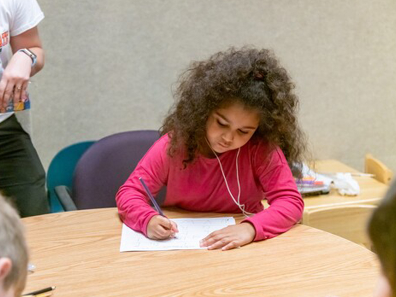 girl writing at a table