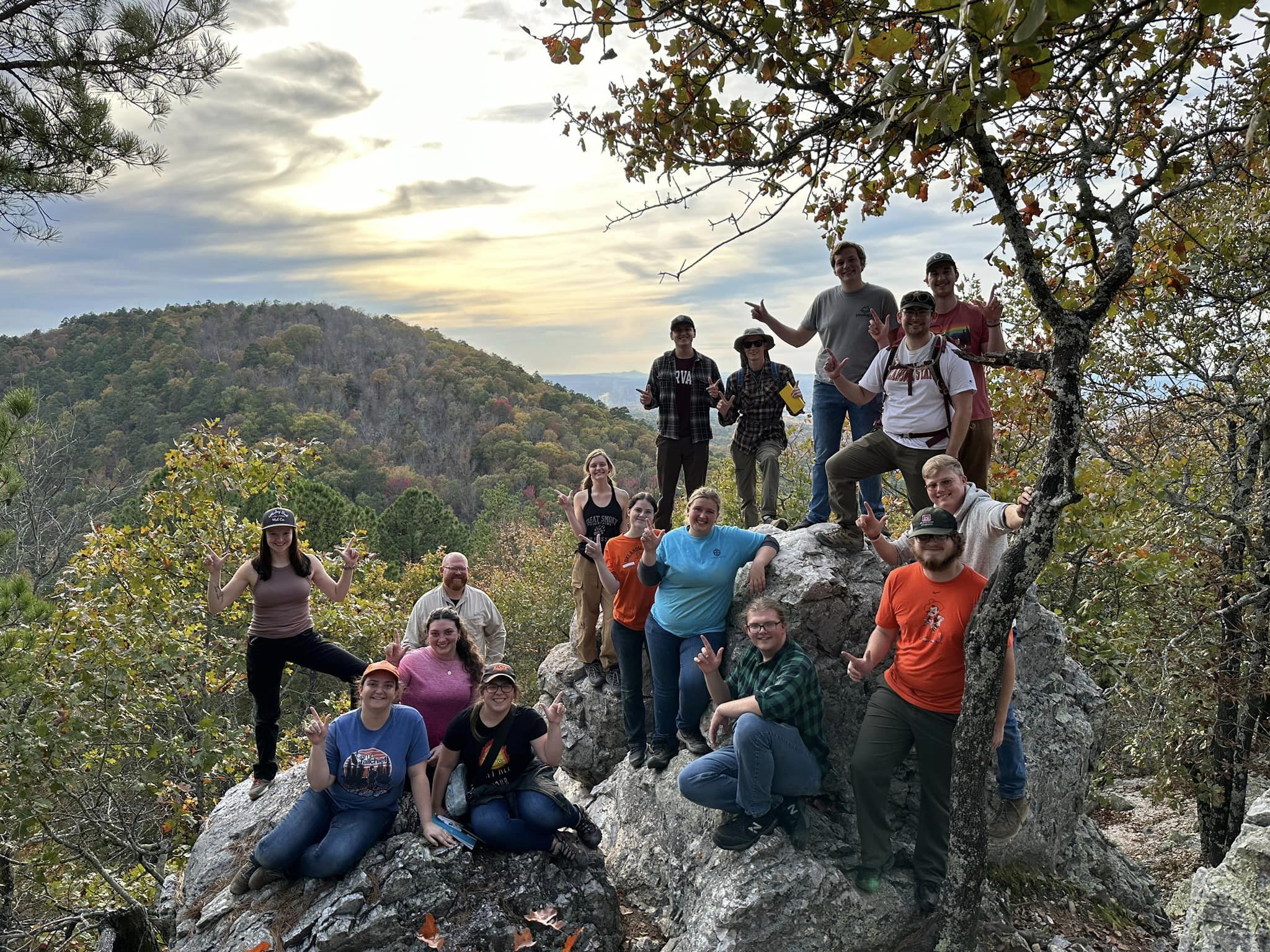 8 male and 7 females students along with one male teacher posing in a group on a rock and mineral field trip.