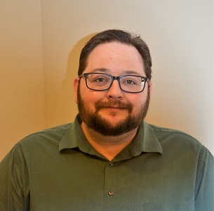 terry.jpg A man with brown hair, beard, and glasses in a green polo shirt stands in front of a neutral backdrop.
