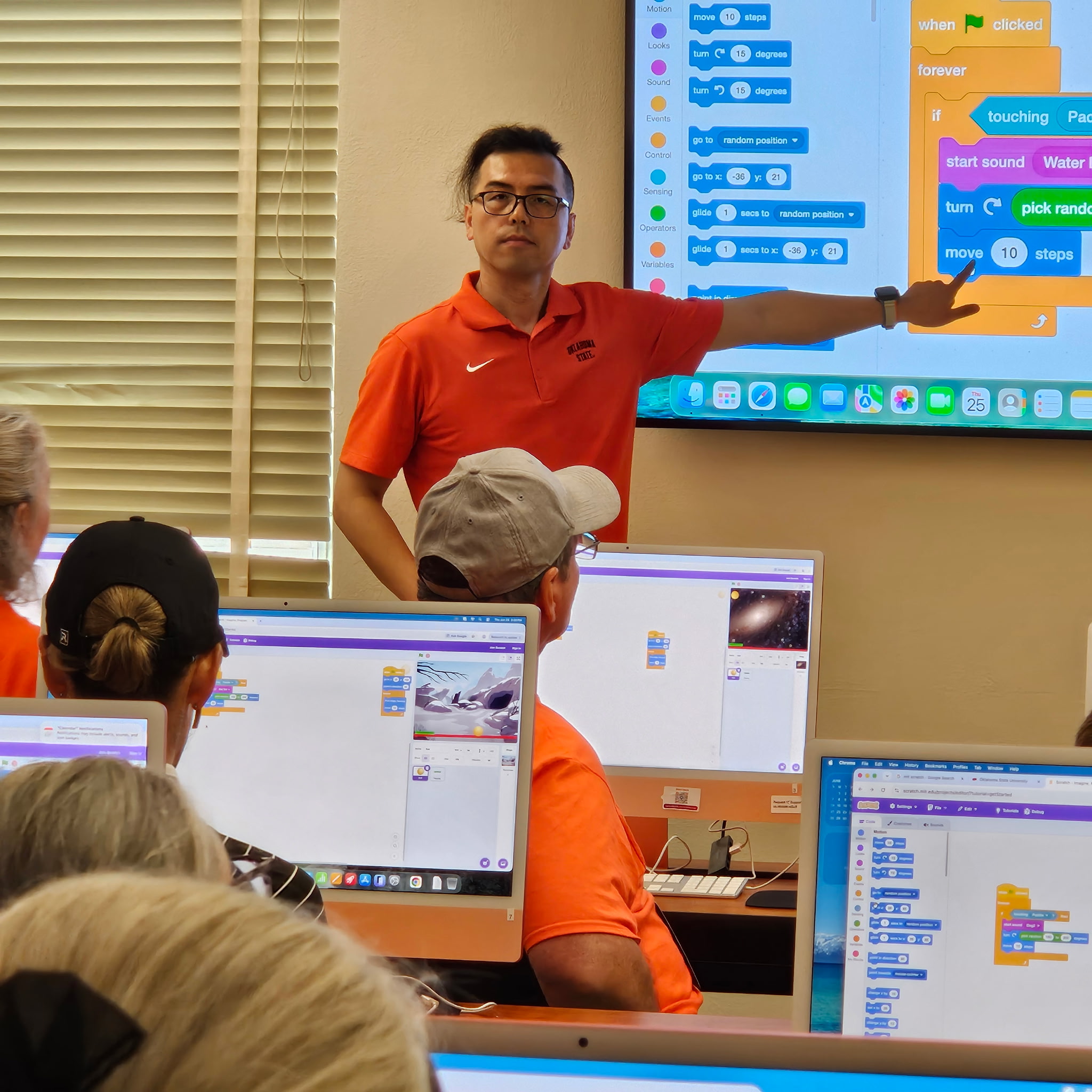 Instructor teaching in a classroom using a projector and whiteboard with displayed text.