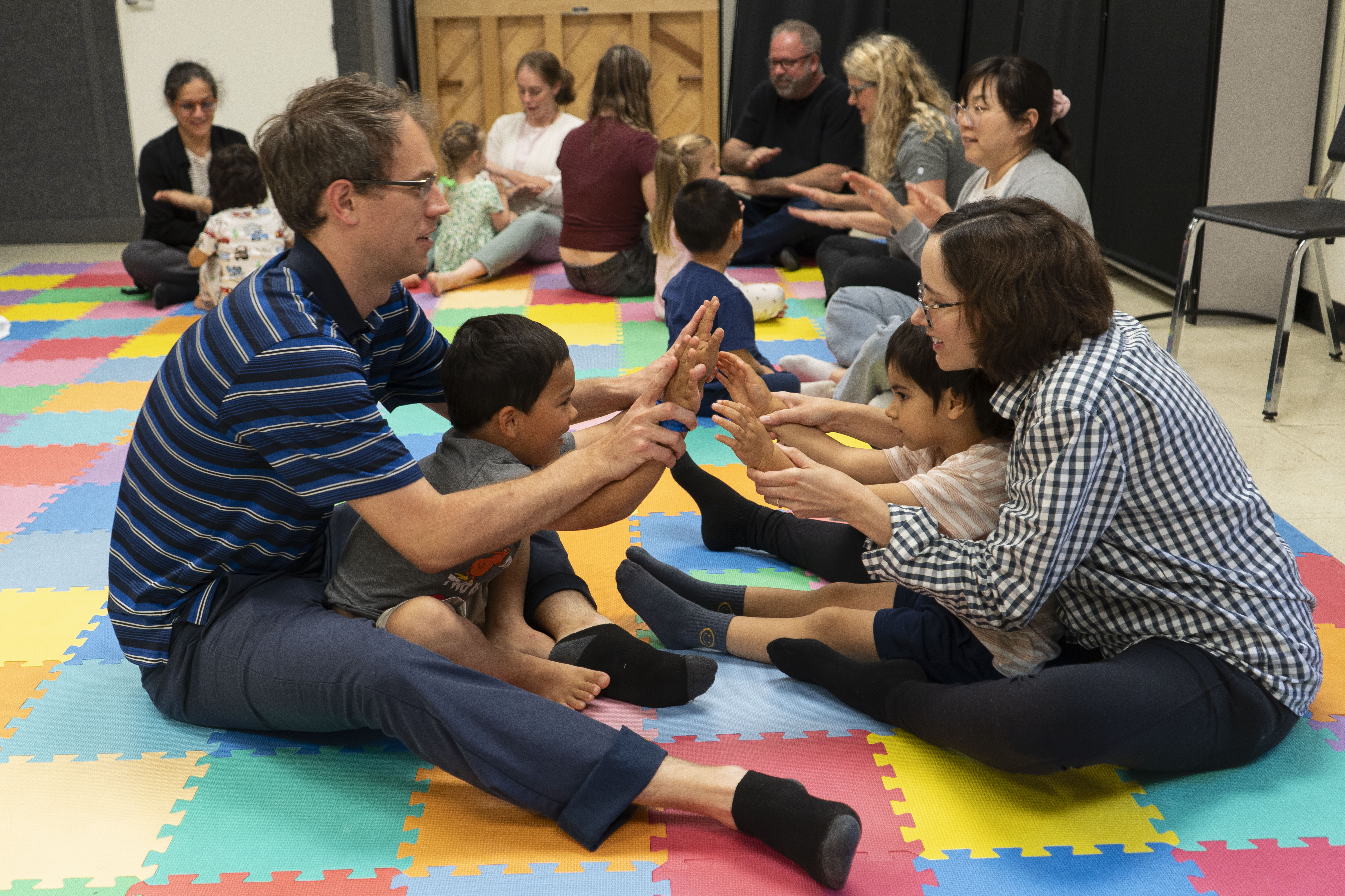 Parents sitting with their child on their lap, facing forward and engaging in a music activity together.