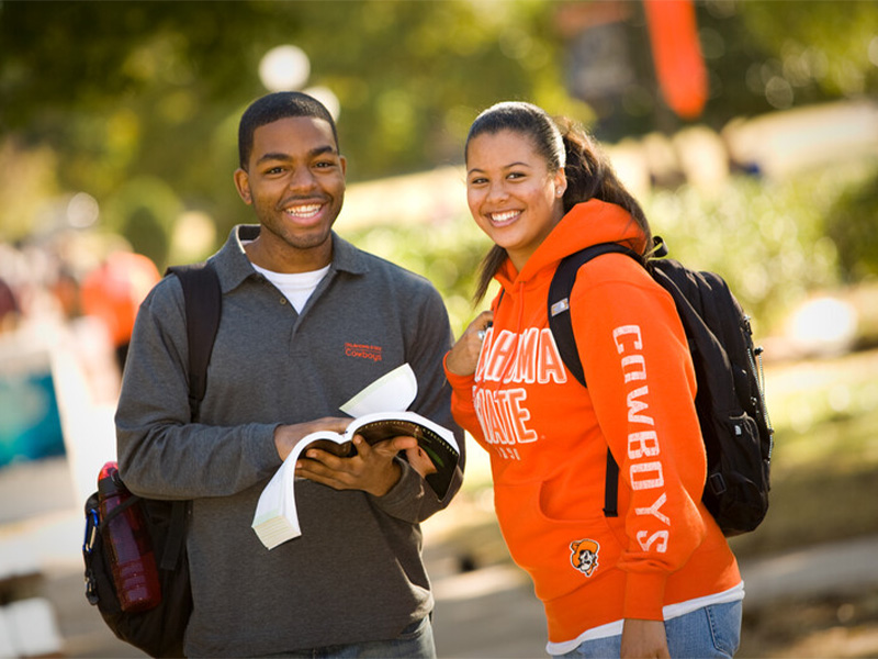 A boy and a girl students, both smiling, holding books in their hands, standing together. A boy and a girl students, both smiling, holding books in their hands, standing together.